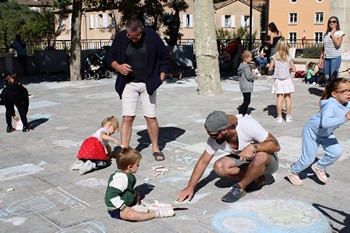 Enfants et adultes dessinent à la craie